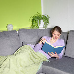 Photo of a woman reading a book on a lounge, recovering from giving birth